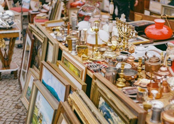 Framed art and ornaments lined up on the table at a flea market.